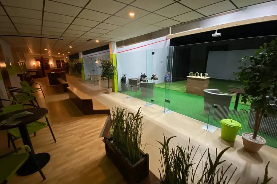 Blick durch den Bistro-Bereich auf den verglasten Green Corner mit Simulator