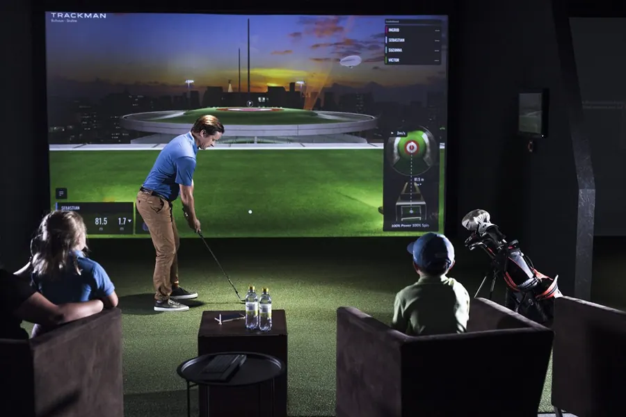 Familie spielt gemeinsam am Simulator, Kinder schauen vom Sessel aus zu