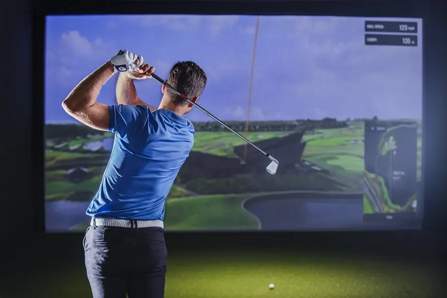 Golfer beim Abschlag am Simulator, rechts die Schlagdaten